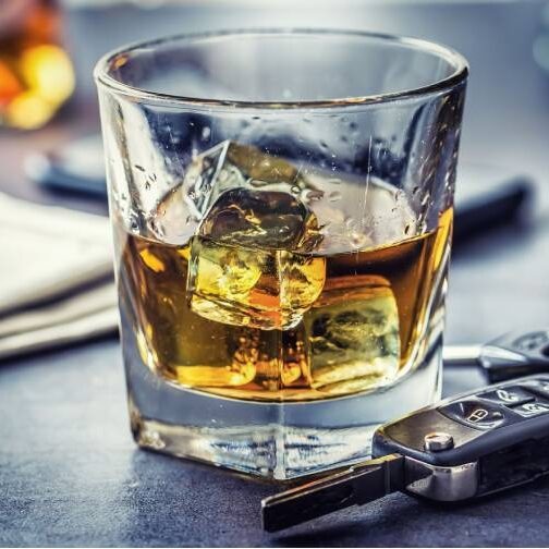 a glass filled with whiskey and iced cubes